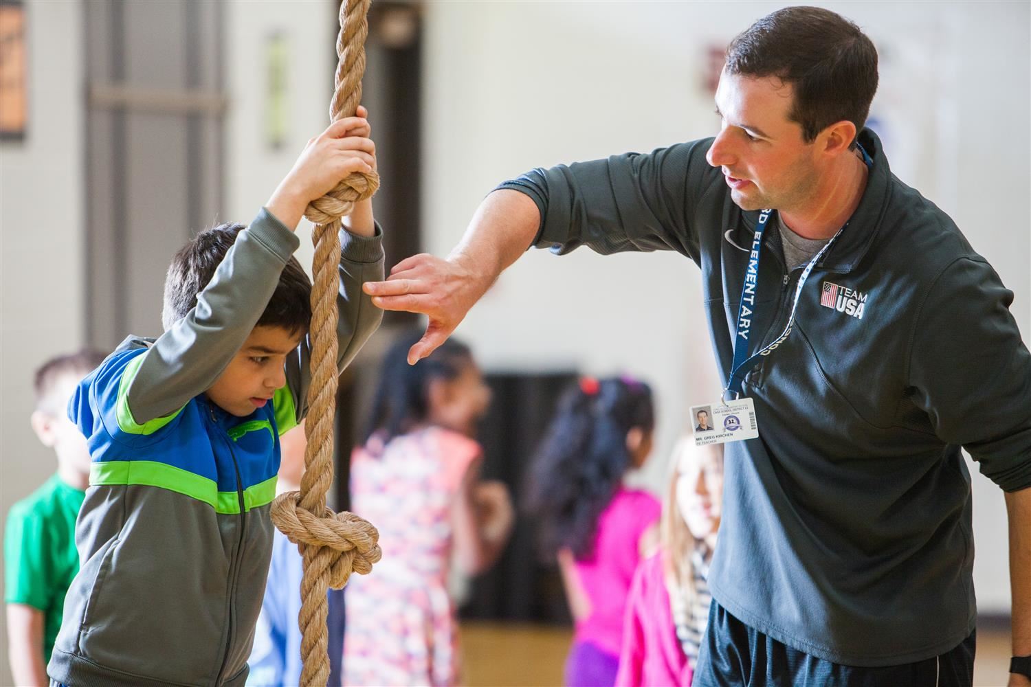 PE teacher and student climbing a rope